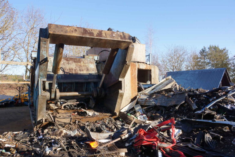 Geöffnete Schrottpresse und davor Altmetall